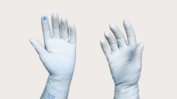 Hand mit Handschuhen und farbig sichtbarer Perforation